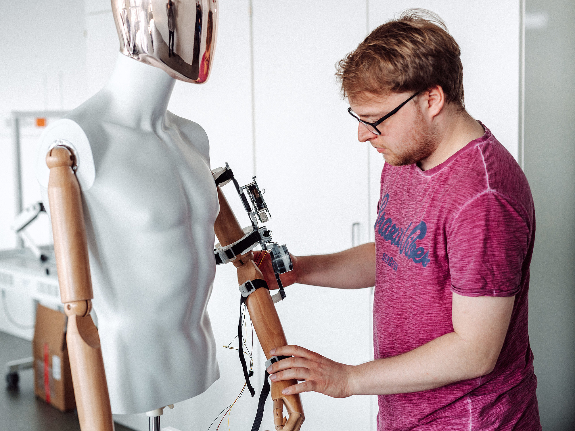 Eine Person schließt technische Geräte an eine menschliche Puppe an.