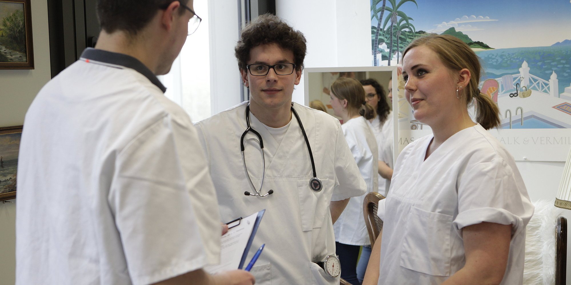 Drei Personen in weißen Kitteln unterhalten sich.