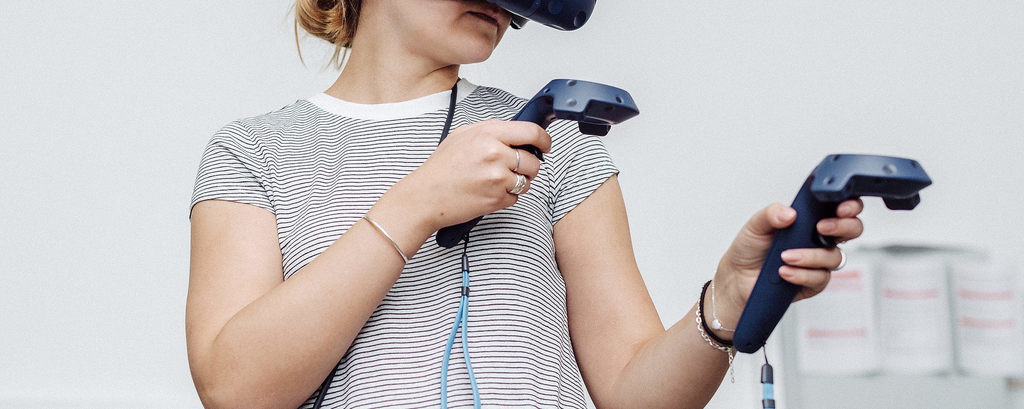 Person trägt VR-Brille und Joysticks in beiden Händen