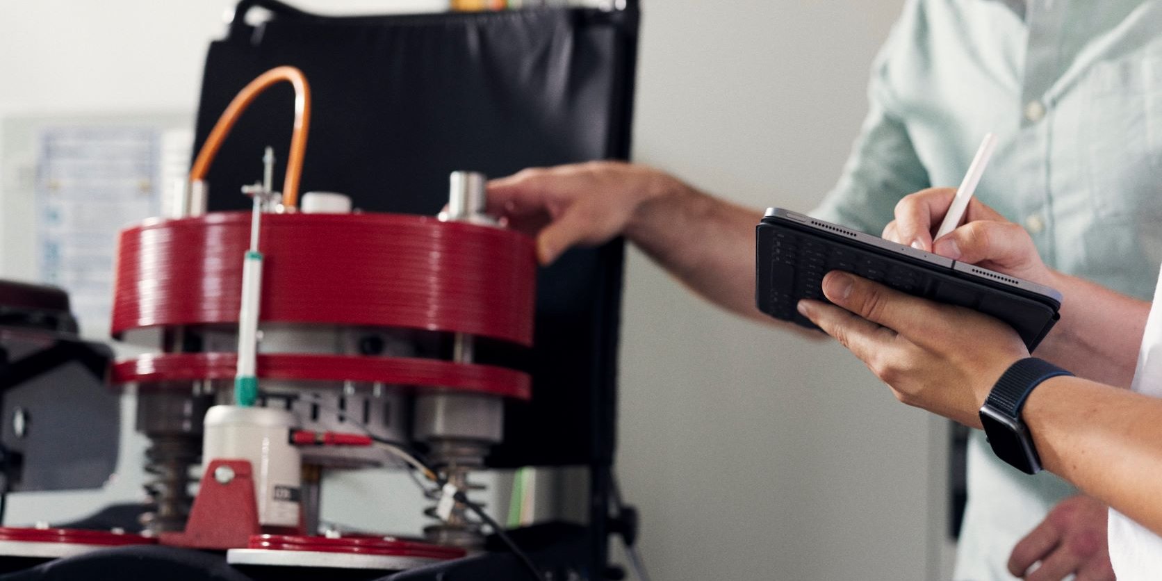 Zwei Personen schauen auf ein Tablet und arbeiten mit einem technischen Rollstuhl