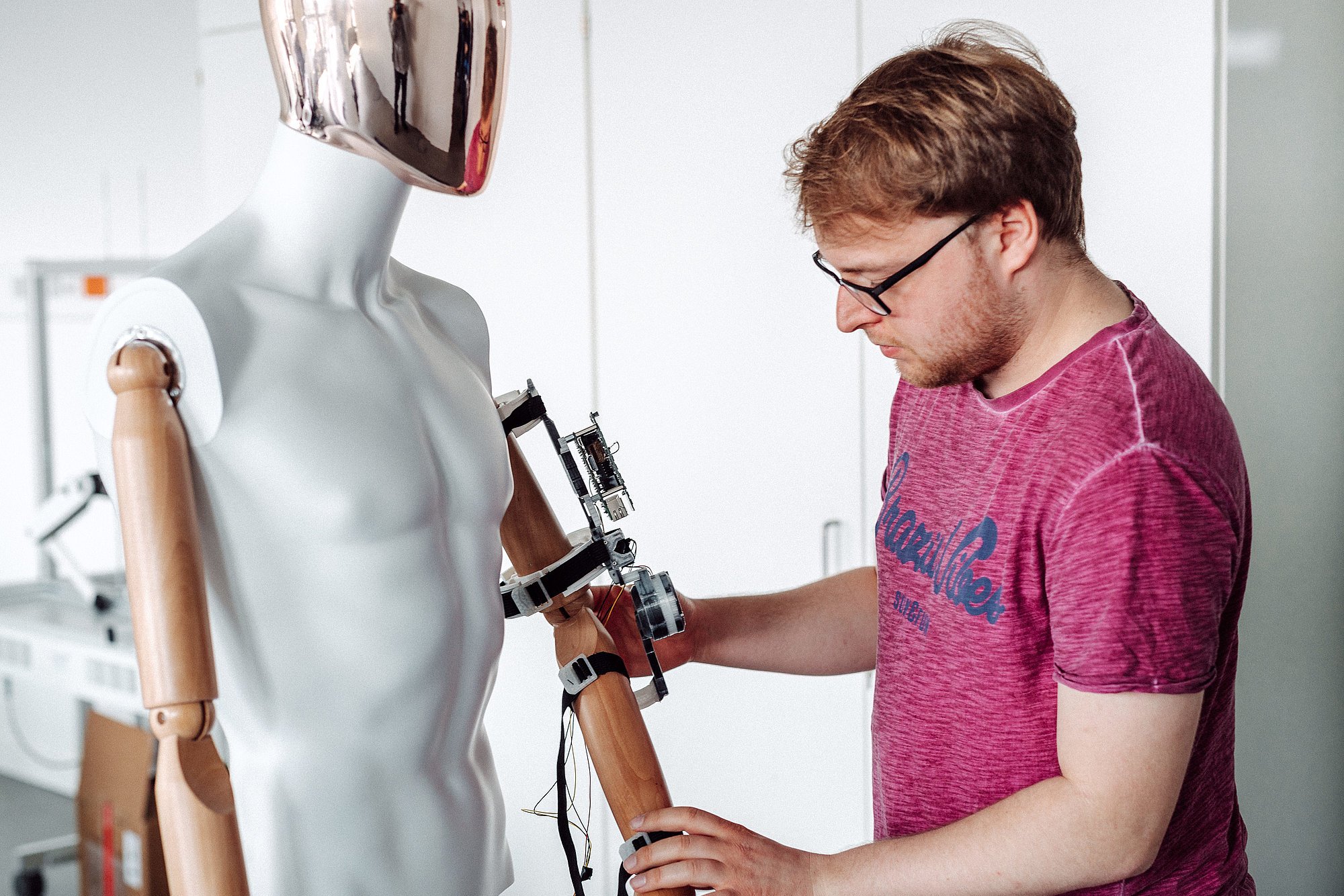 Eine Person schließt technische Geräte an eine menschliche Puppe an.